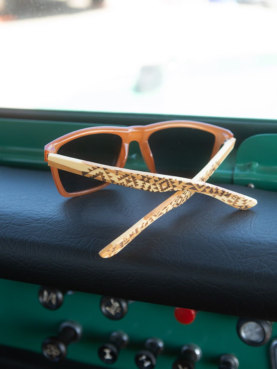 Polarized sunglasses with orange frames, dark lenses, and patterned temple arms