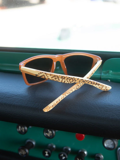 Polarized sunglasses with orange frames, dark lenses, and patterned temple arms