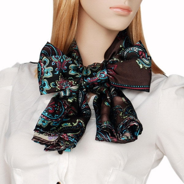 Paisley silk scarf in dark tones with teal and pink tied in a bow at collar