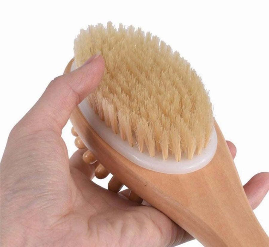 Close-up of wooden bath massage brush with tan bristles and rounded head
