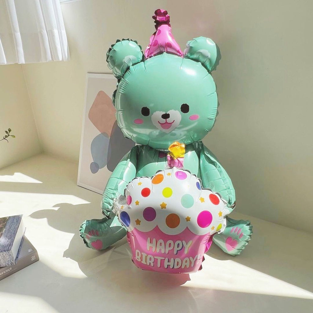 Teal bear-shaped foil balloon holding a polka-dot cake, pink "Happy Birthday" banner