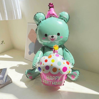 Teal bear-shaped foil balloon holding a polka-dot cake, pink "Happy Birthday" banner