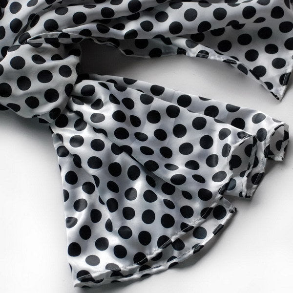 Large silk scarf close-up, black polka dots pattern on white fabric wrap