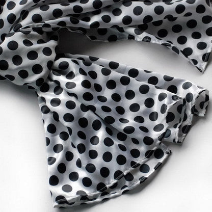 Large silk scarf close-up, black polka dots pattern on white fabric wrap