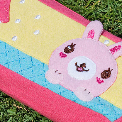Close-up embroidered rabbit face on pencil pouch, teal-blue quilted fabric with pink border