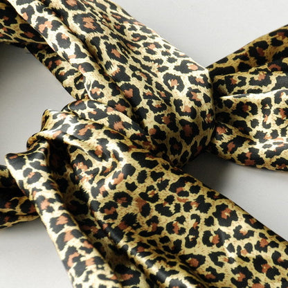 Leopard-print scarf close-up with glossy gold, tan, and dark brown pattern folds