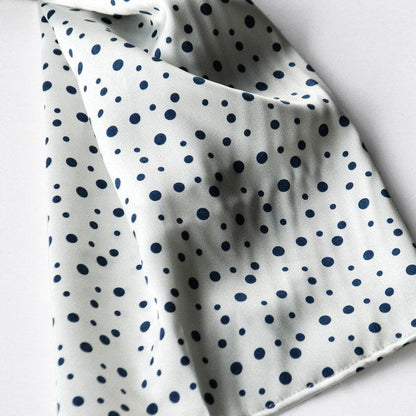 Silk scarf fabric close-up: white with small black dot pattern.