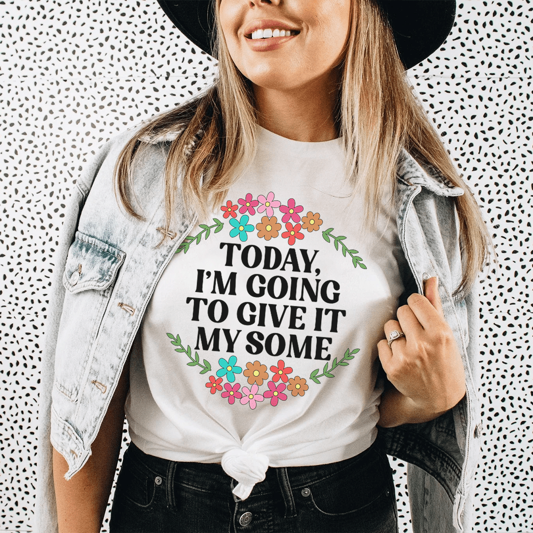 White graphic T-shirt with floral wreath and bold slogan text centered, crew neck