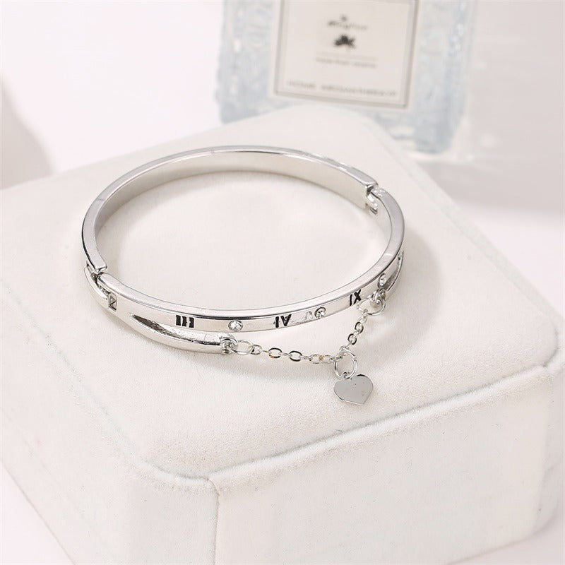 Silver-tone bangle bracelet with roman numerals and heart pendant on a chain