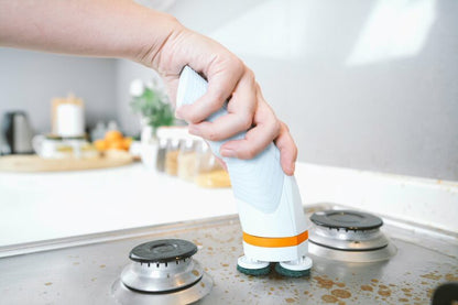 Ice blue scrub brush scrubbing around stovetop burners