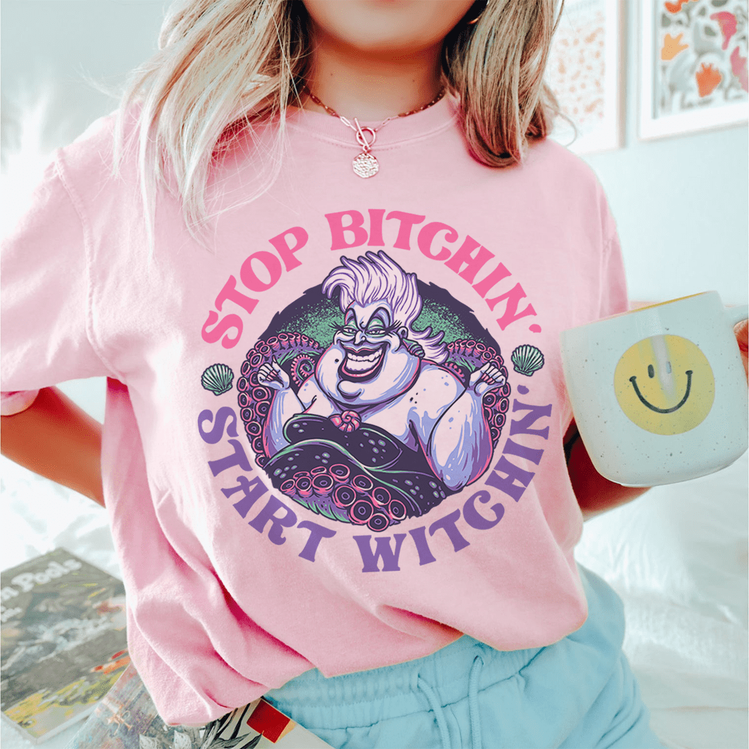 Pink T-shirt with large witch cartoon graphic and arched purple lettering
