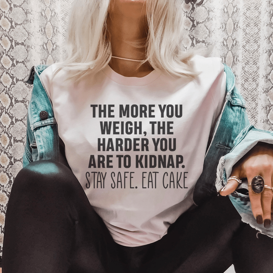 Light-colored crewneck T-shirt on model, black quote print: THE MORE YOU WEIGH... EAT CAKE.