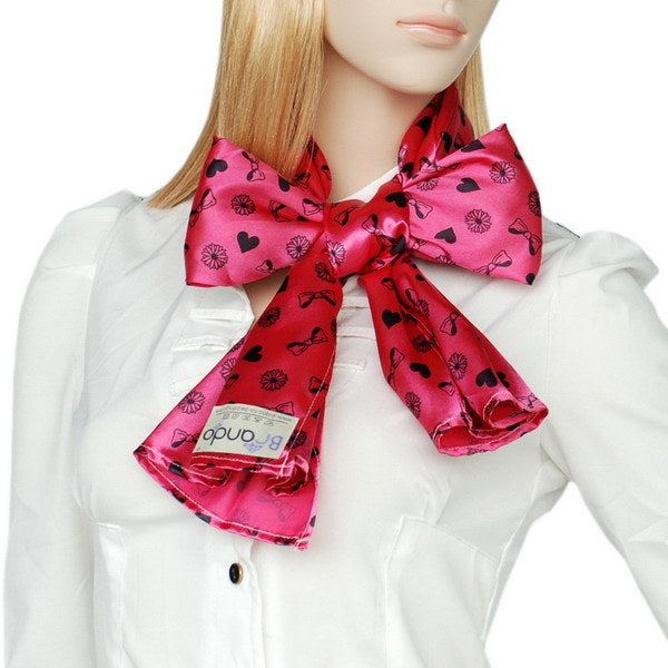 Pink silk scarf bow-tie with heart-and-flower print, worn over shirt collar