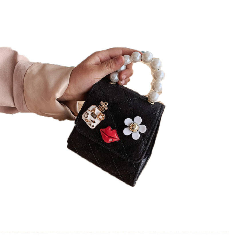 Black mini quilted crossbody bag with pearl top handle, lip charm, and flower detail