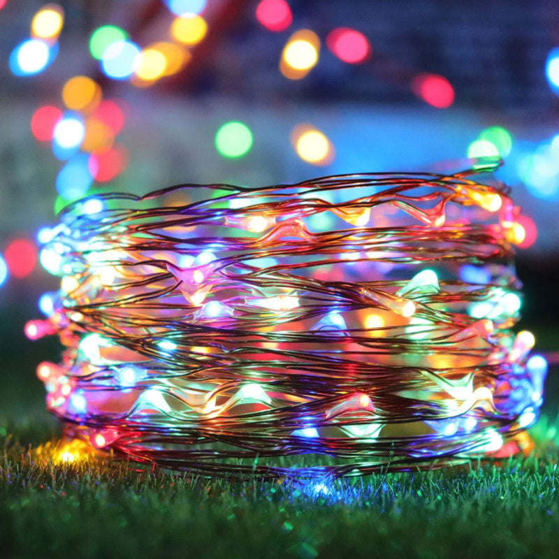 Solar string lights with multicolor wire strands and small glowing bulbs on grass.