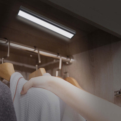 Rechargeable motion LED light bar above bed with hand reaching toward the light