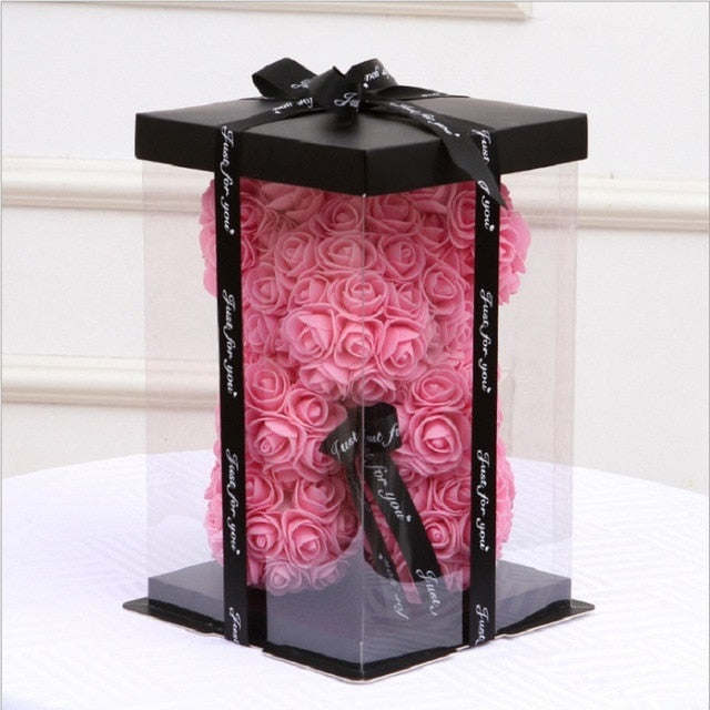 Gift box with black lid and bow, revealing a pink rose teddy bear inside