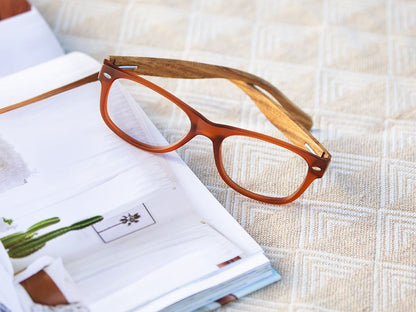 Blue-light reading glasses with brown and orange frame, resting on fabric