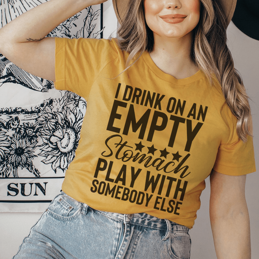Mustard T-shirt worn by model with bold “EMPTY” and “Stomach” front graphic