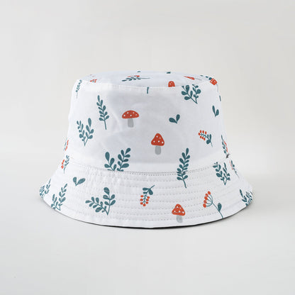 White bucket hat with green leaves and red mushroom print, wide brim