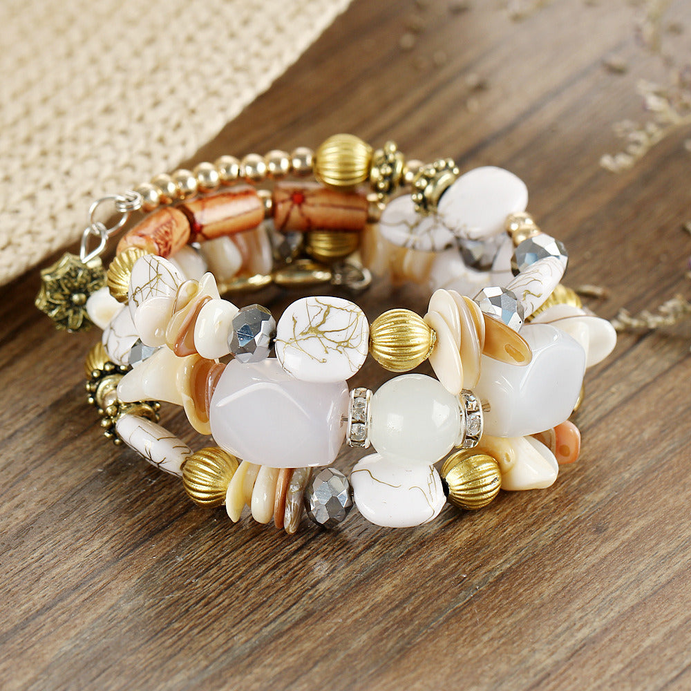 Multilayer beaded charm bracelet with white cabochons, gold beads, and crystal shell accents