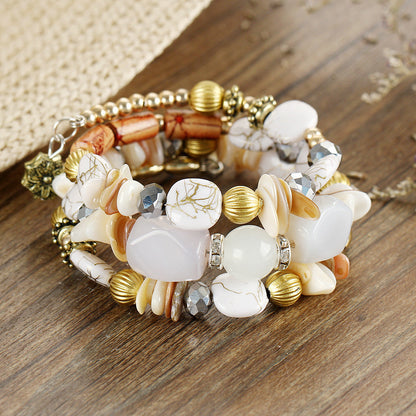 Multilayer beaded charm bracelet with white cabochons, gold beads, and crystal shell accents