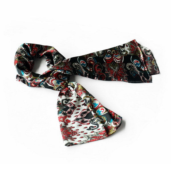Large paisley scarf in dark tones with red, teal, and white swirls, loosely tied.