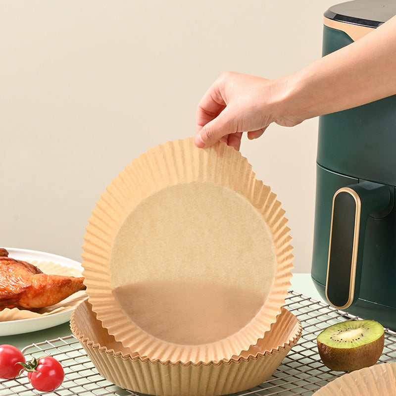 Hand placing a round beige paper liner mat into an air fryer basket for non-stick cooking