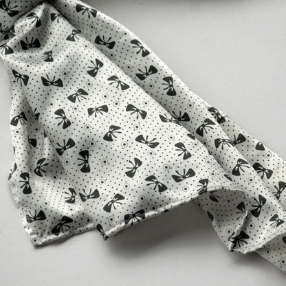 White silk scarf with black bow and dotted pattern, soft folded corner