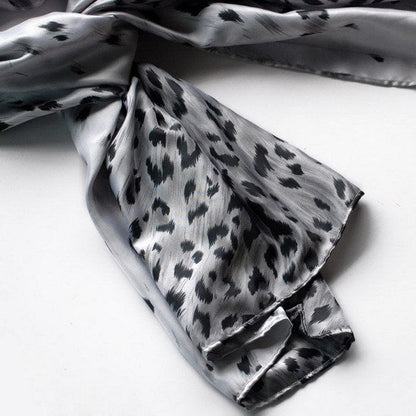 Silver-gray silk scarf with black leopard spots, folded with visible edge