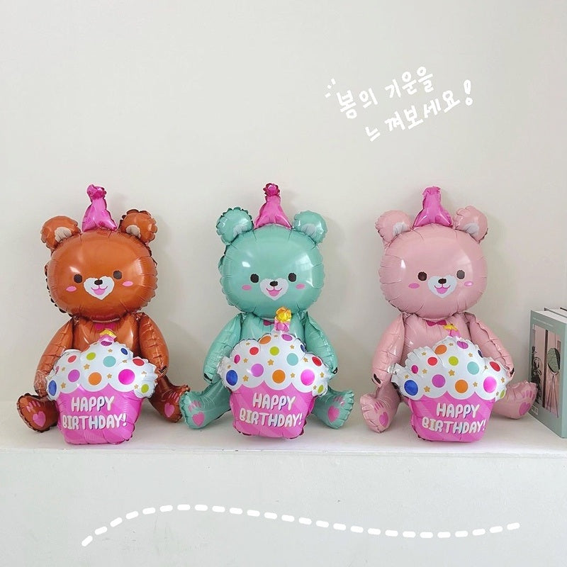 Three bear-shaped foil balloons standing side by side: orange, teal, and pink, "Happy Birthday"