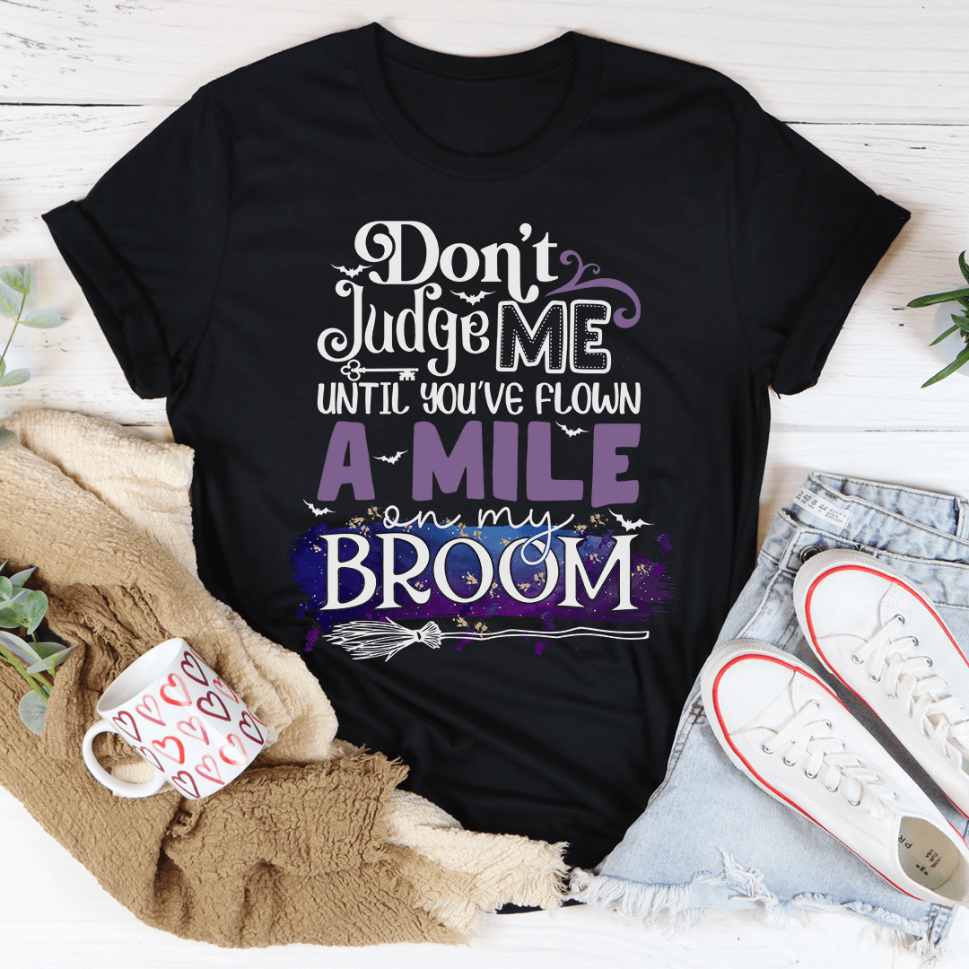 Black crewneck T-shirt with purple and white broom graphic, slogan text front