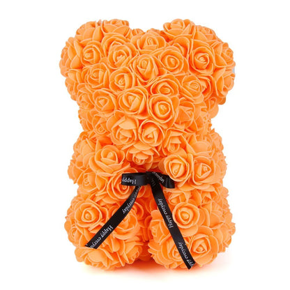 Orange rose teddy bear with layered rose petals and a black ribbon bow at the chest