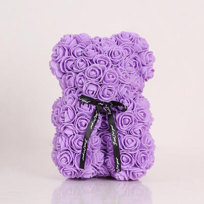 Rose teddy bear in light purple with layered rose petals and a black bow ribbon