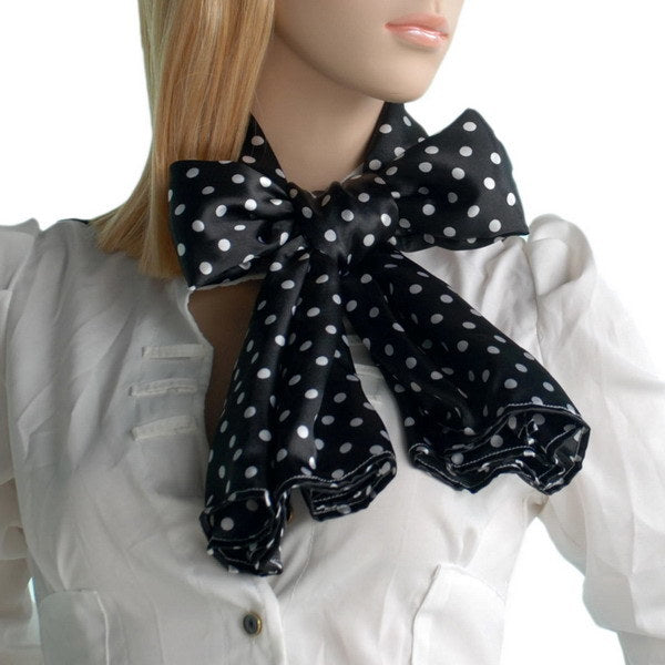 Black silk scarf with white polka dots, tied in a bow at the neck