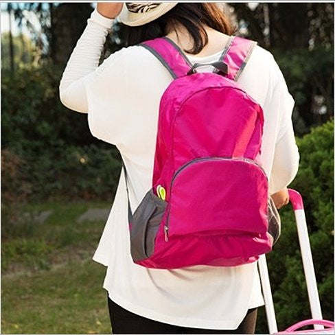 Hot pink folding backpack with front pocket and two zippers; padded back and shoulder straps.