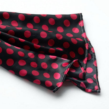 Silk scarf corner with red polka dots on dark black fabric