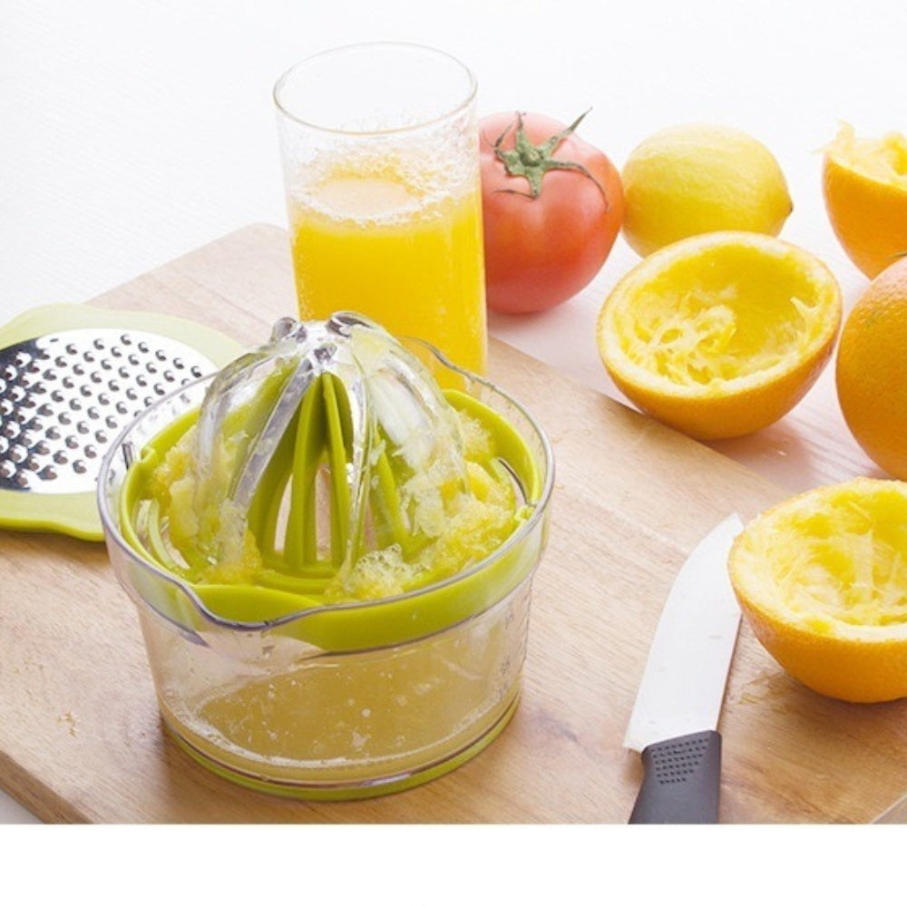 Green manual citrus squeezer with cone and measuring cup on a wooden board, with juice.
