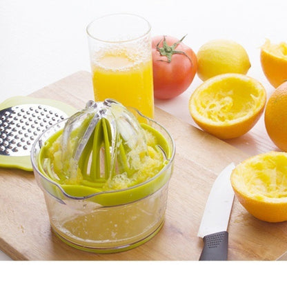 Green manual citrus squeezer with cone and measuring cup on a wooden board, with juice.