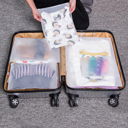 Clear clothing storage bags with printed owl sheets inside an open suitcase