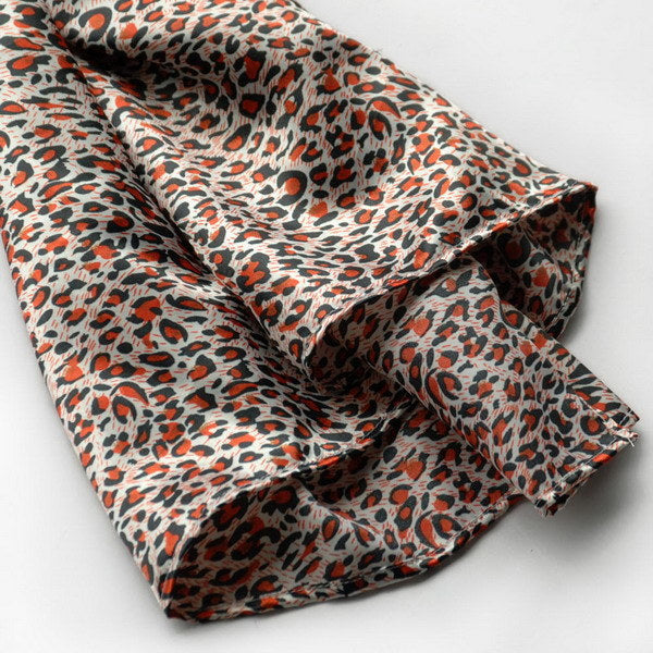 Leopard-pattern silk scarf corner with orange and black spots on cream