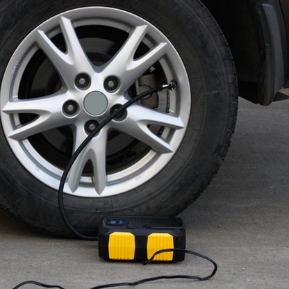 Yellow-and-black tire inflator pump connected to a car wheel valve with hose