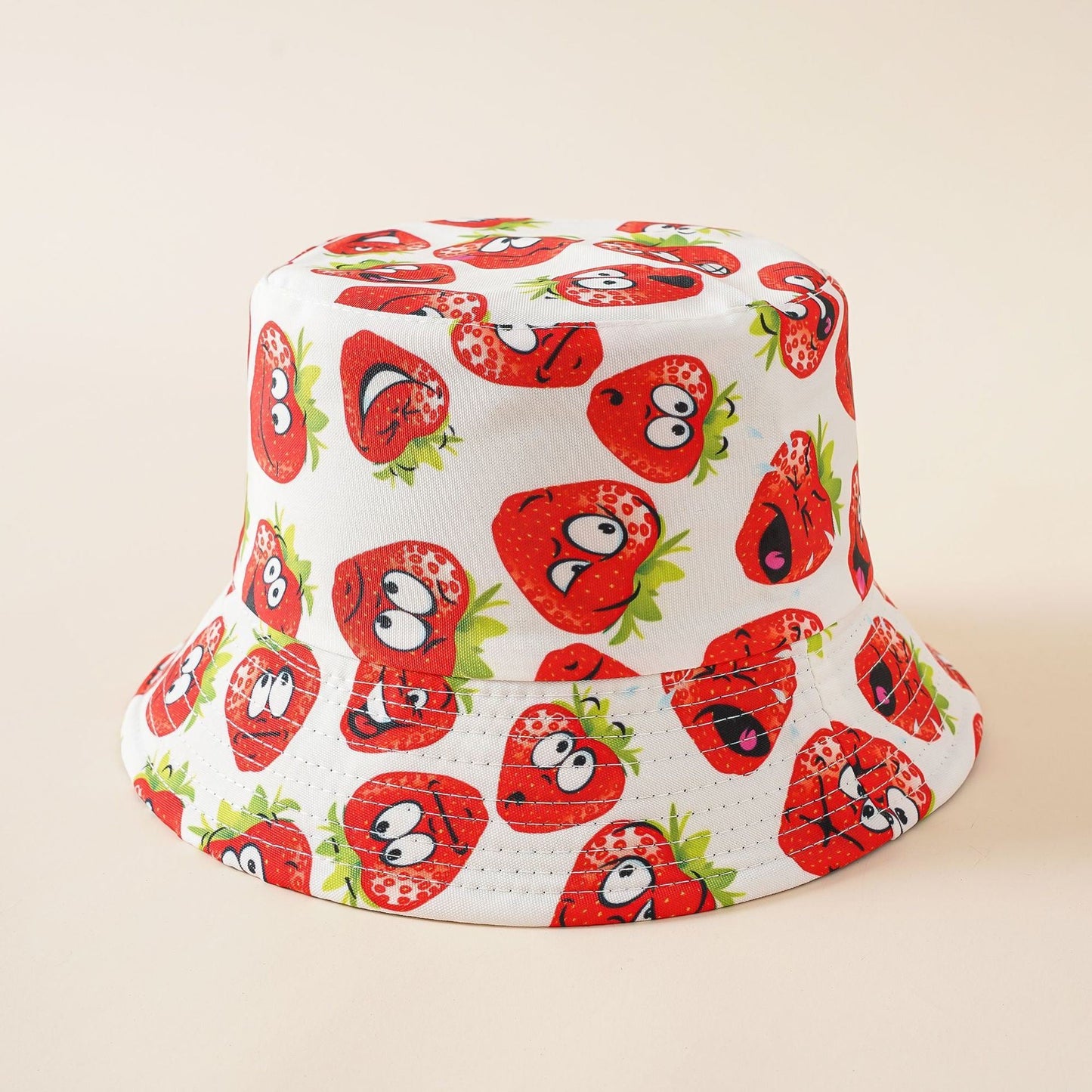 White bucket hat with cartoon strawberry faces and red fruit pattern