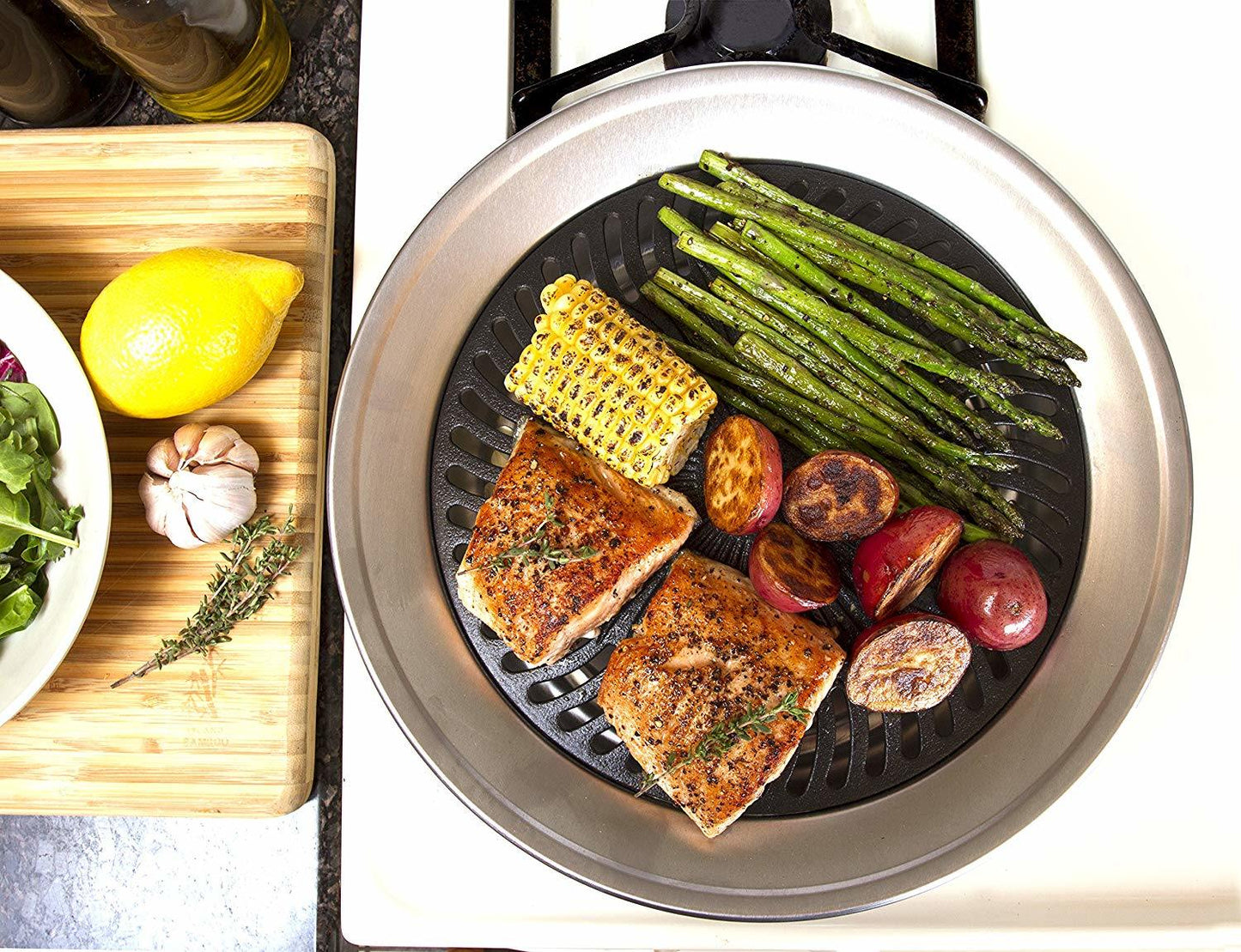 Round smokeless grill with cooked fish, asparagus, and mushrooms on black grate
