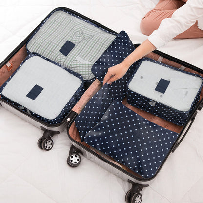 Navy polka dot packing cube set with zip compartments, stored in a rolling suitcase