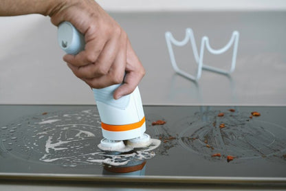Cordless spin scrub brush cleaning a sink drain area with rotating pads