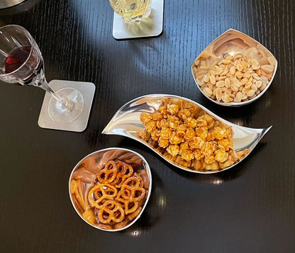 Wavy snack nut bowl, reflective silver dish filled with nuts and snacks