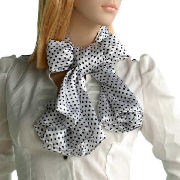 White scarf with black polka dots, tied in a bow at the neck