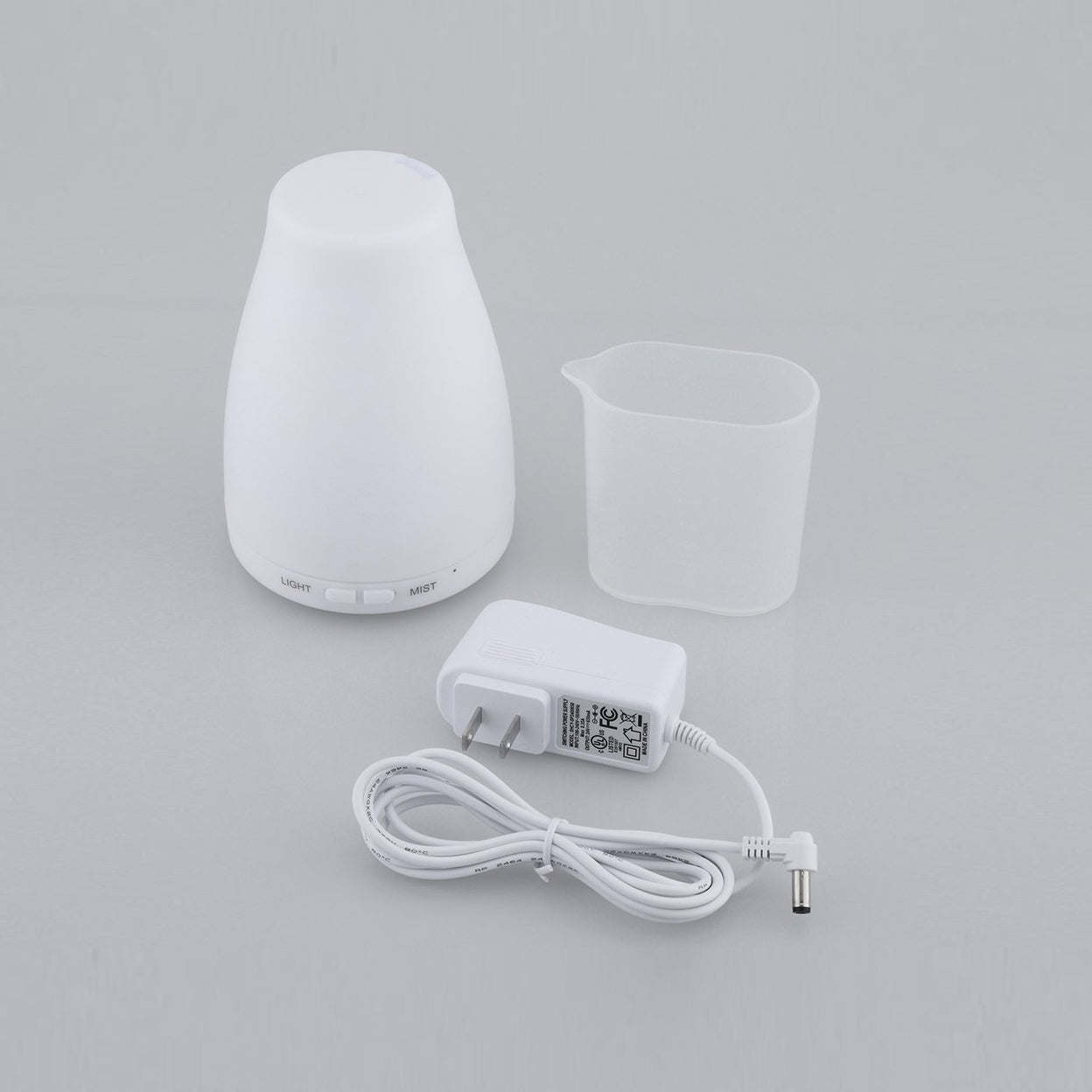 Aromatherapy-free humidifier, plus empty reservoir cup and power adapter.
