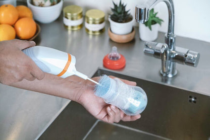 Cordless spin scrub brush in use on a kitchen sink counter with orange accents